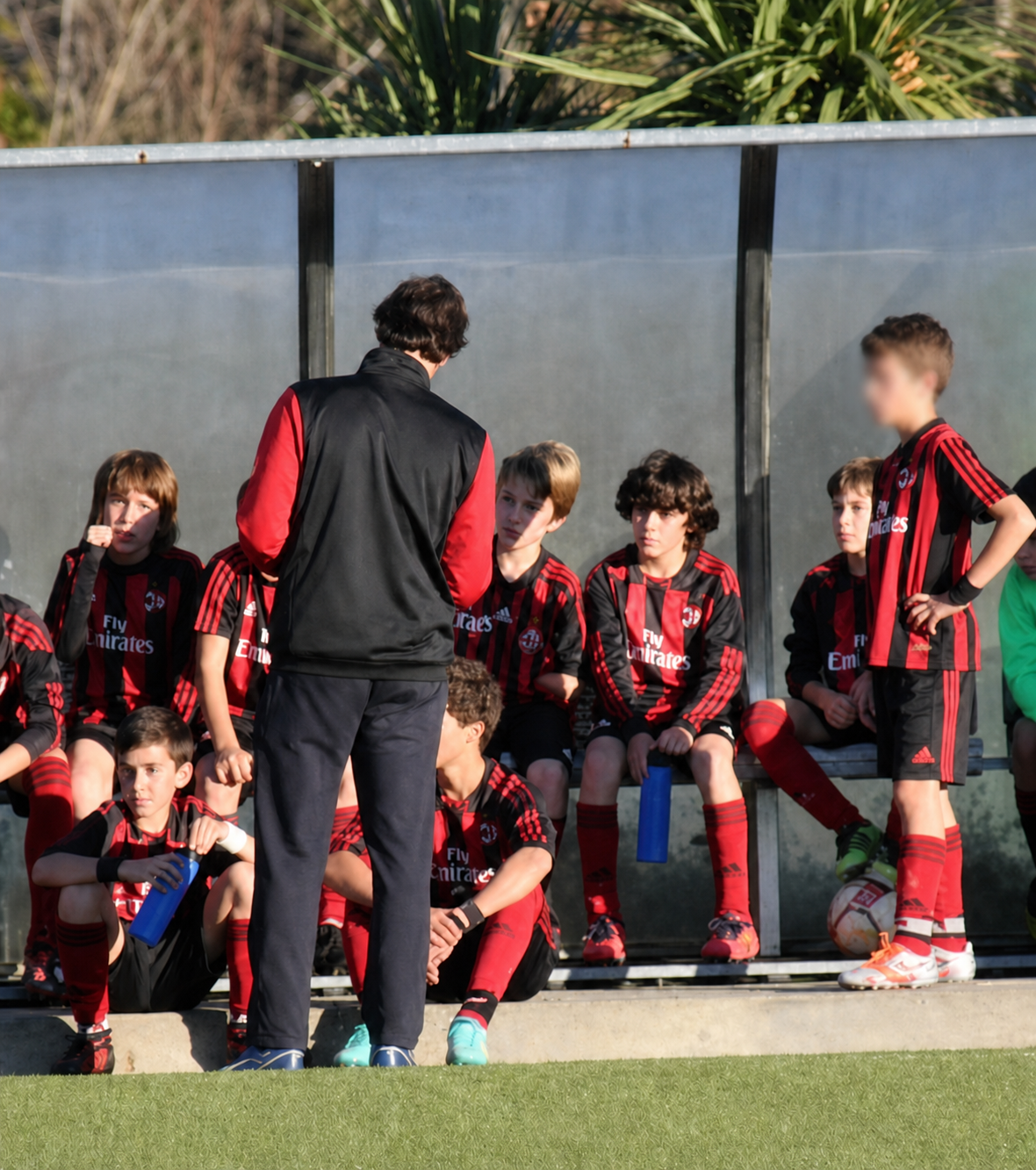 Treinador junto de jovens jogadores num banco de suplentes