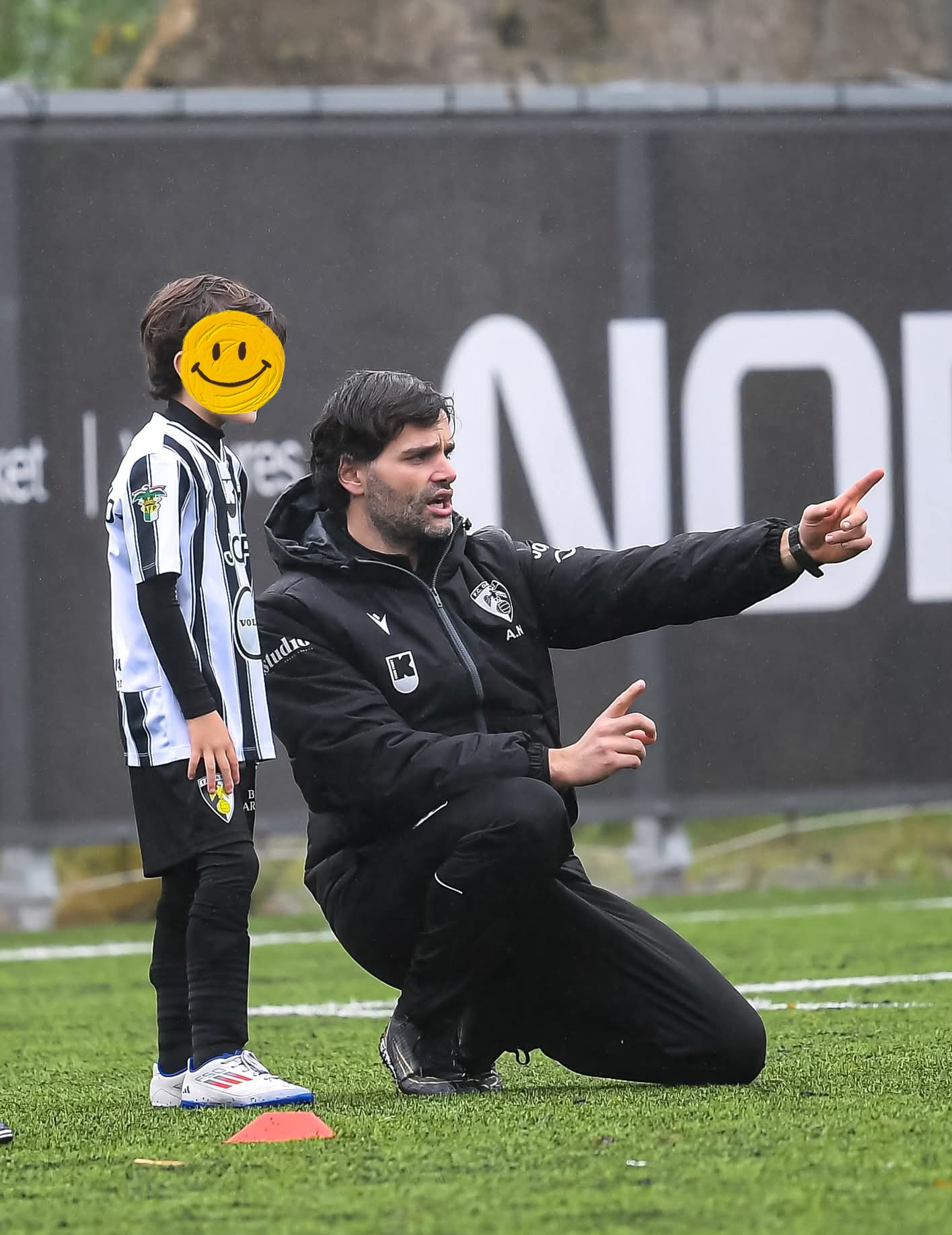 Treinador a orientar jovem atleta durante um jogo de futebol