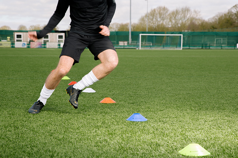 Jogador de futebol a treinar com cones num campo